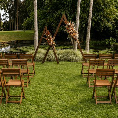 Outdoor wedding setup with wooden chairs and floral arches in a garden.