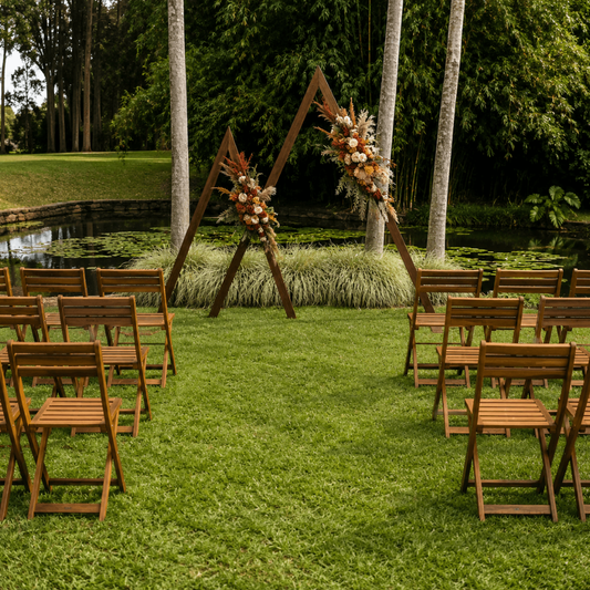 Outdoor wedding setup with wooden chairs and floral arches in a garden.