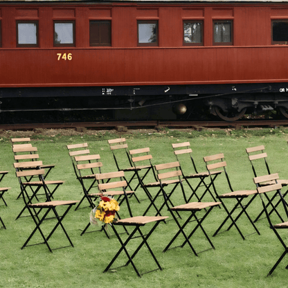 Set of folding chairs arranged in front of a red train car on grass