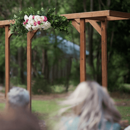 Wooden arch with floral decorations in a forest setting