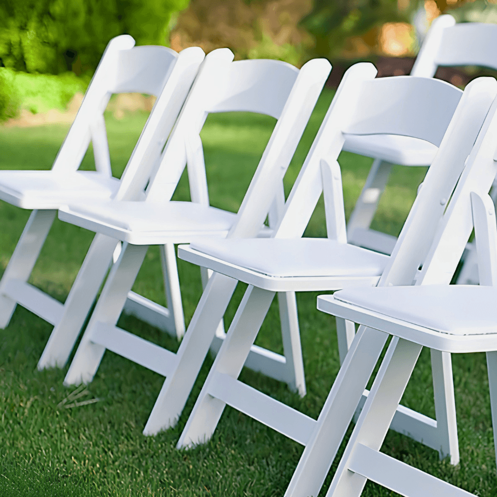 White folding chairs arranged on a grassy area