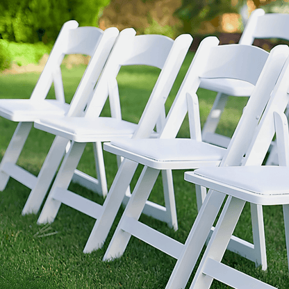 White folding chairs arranged on a grassy area